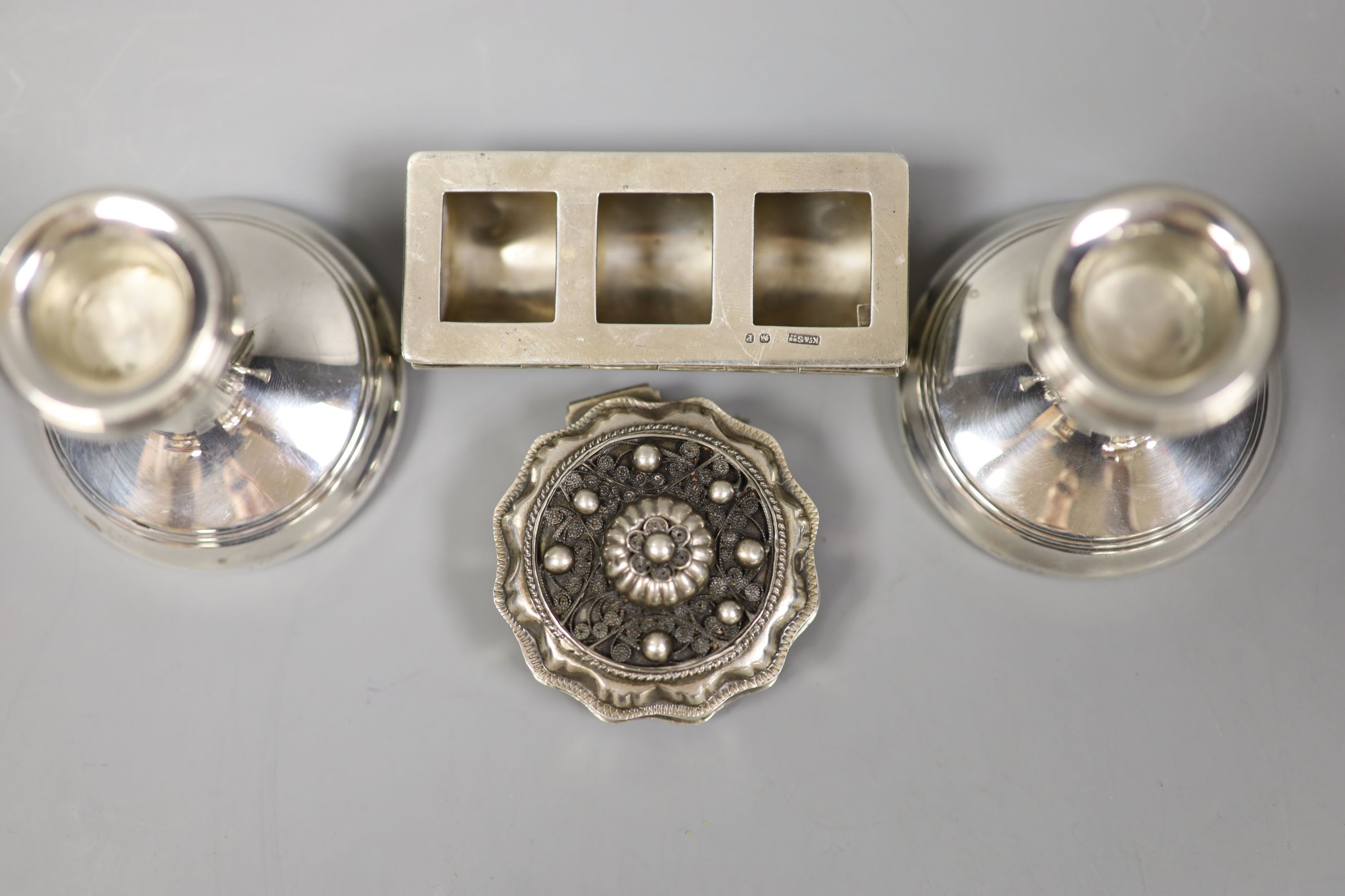 A pair of silver mounted dwarf candlesticks, 71mm, a late Victorian silver three division stamp box and a continental pill box.